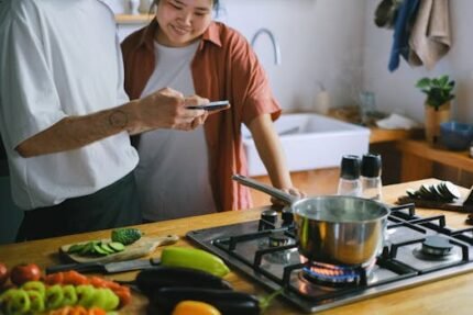 A couple cooking together and using a smartphone for recipes in a cozy kitchen.